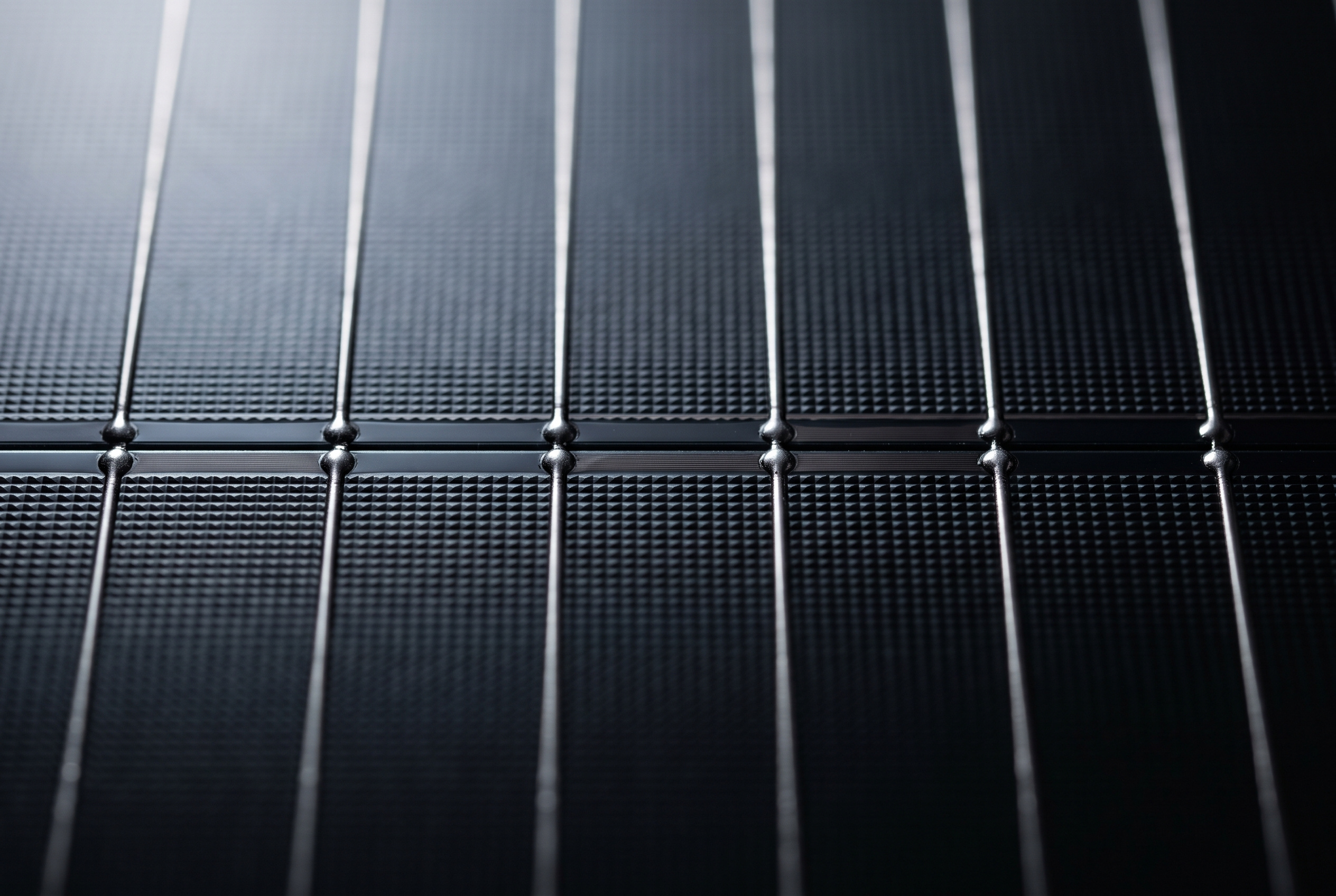 Makro detail černého N-type článku - multi-busbar dráty a předěl mezi půlkami článku